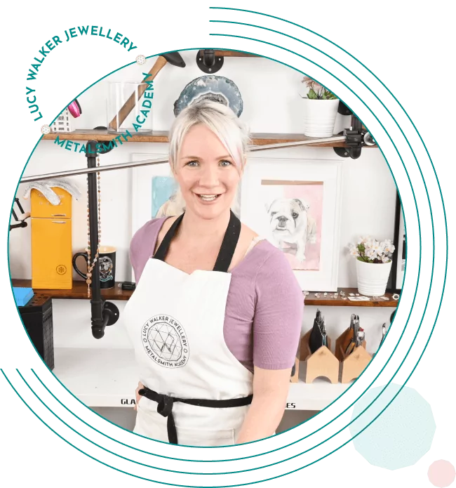 A person in an apron smiles in a workshop with various tools and artworks in the background.  From a guide on jewelry making tools.